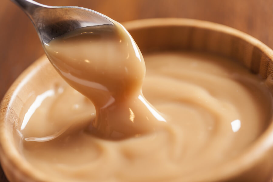 The creamy and sweet Dulce de Leche cream in a wooden bowl.