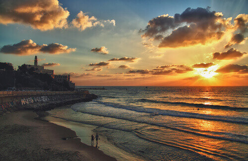 Silhouette of a young couple walking on the beach against a beautiful sunset near Old Jaffa.