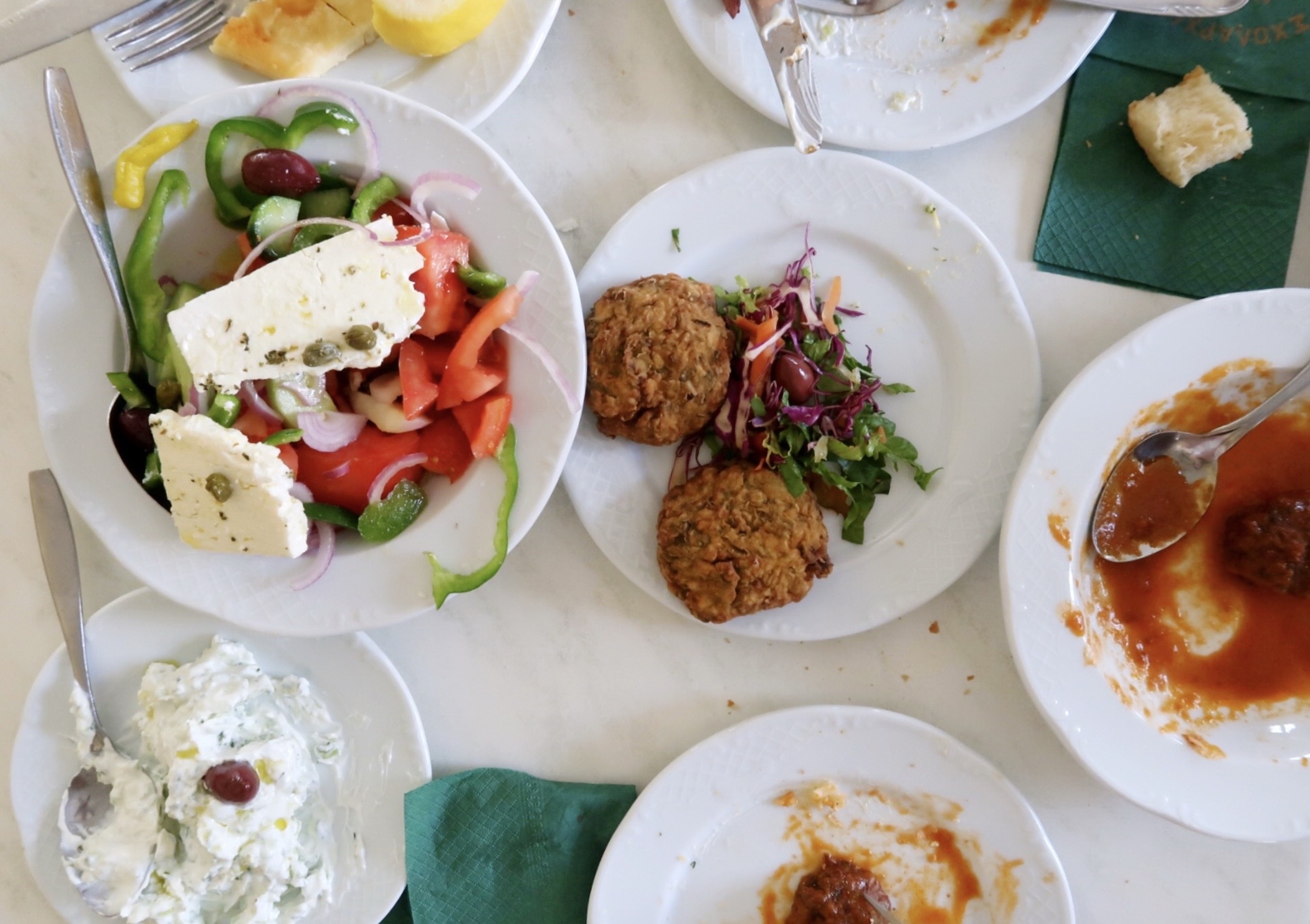 Greek salad with feta, tomato fritters, tzatziki, and assorted meze on a table in a Santorini taverna