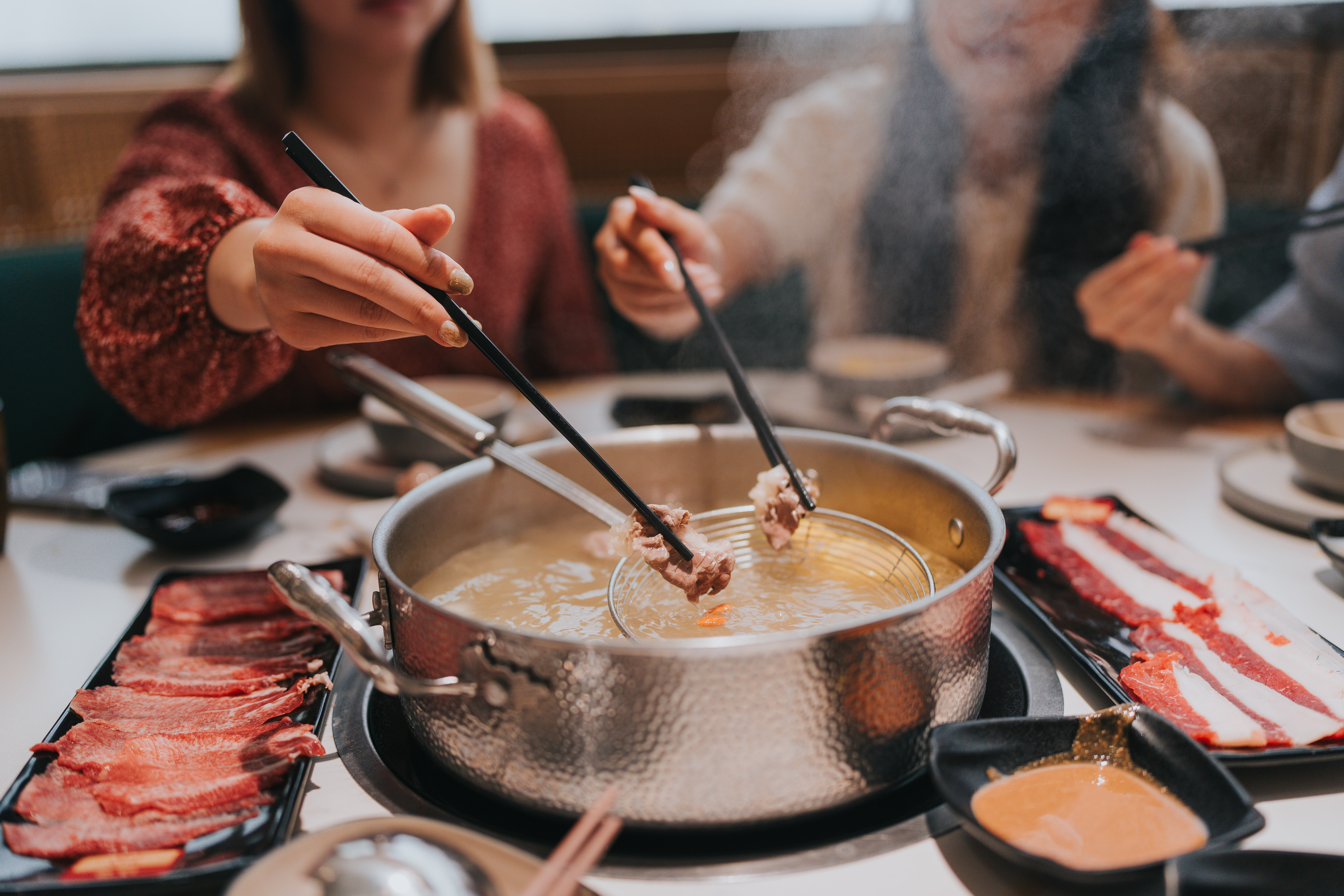 A steaming hot pot filled with fresh vegetables and meat