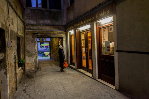 A woman looks into the window of the kosher Gam Gam Bar in the Jewish Quarter of Venice.