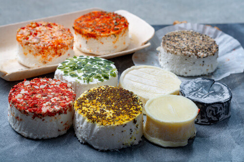A colourful assortment of fresh white soft goat cheeses with different toppings