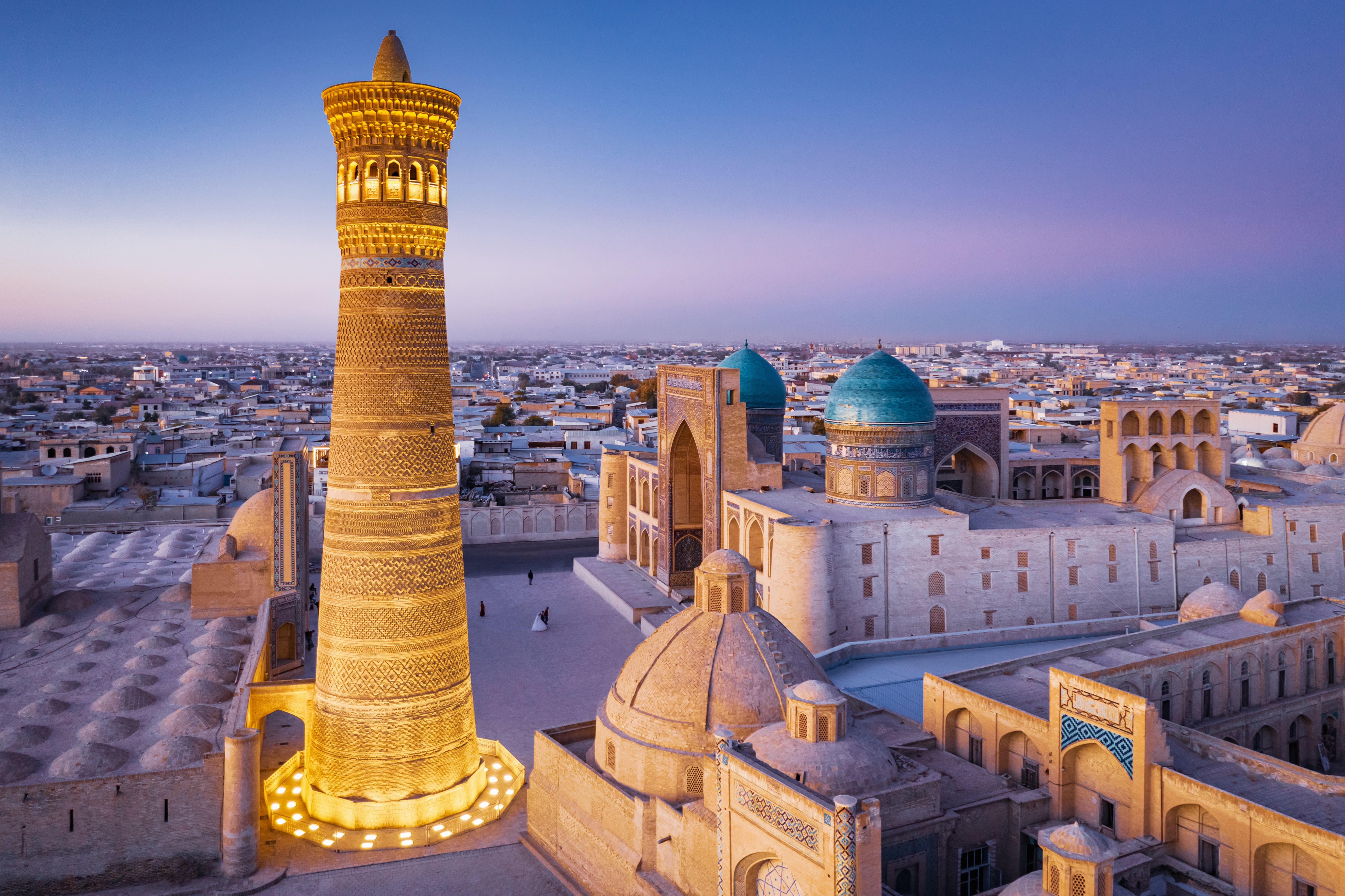 Illuminated Kalyan Minaret and surrounding domes in Bukhara at twilight, a highlight of Bukhara sightseeing