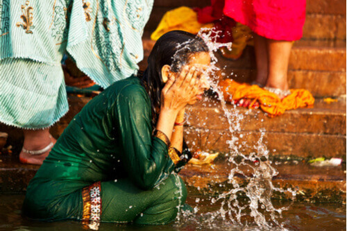 A local woman washes her face in the Ganges River.