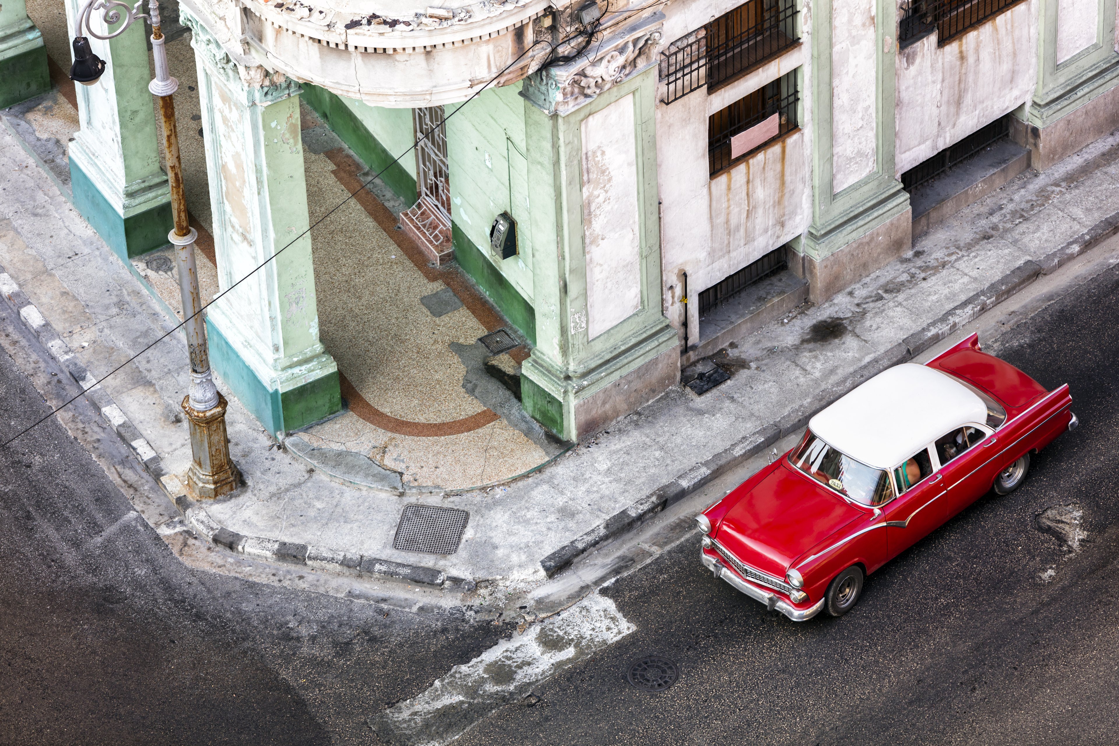 A classic red vintage car cruises through the colourful streets of Havana