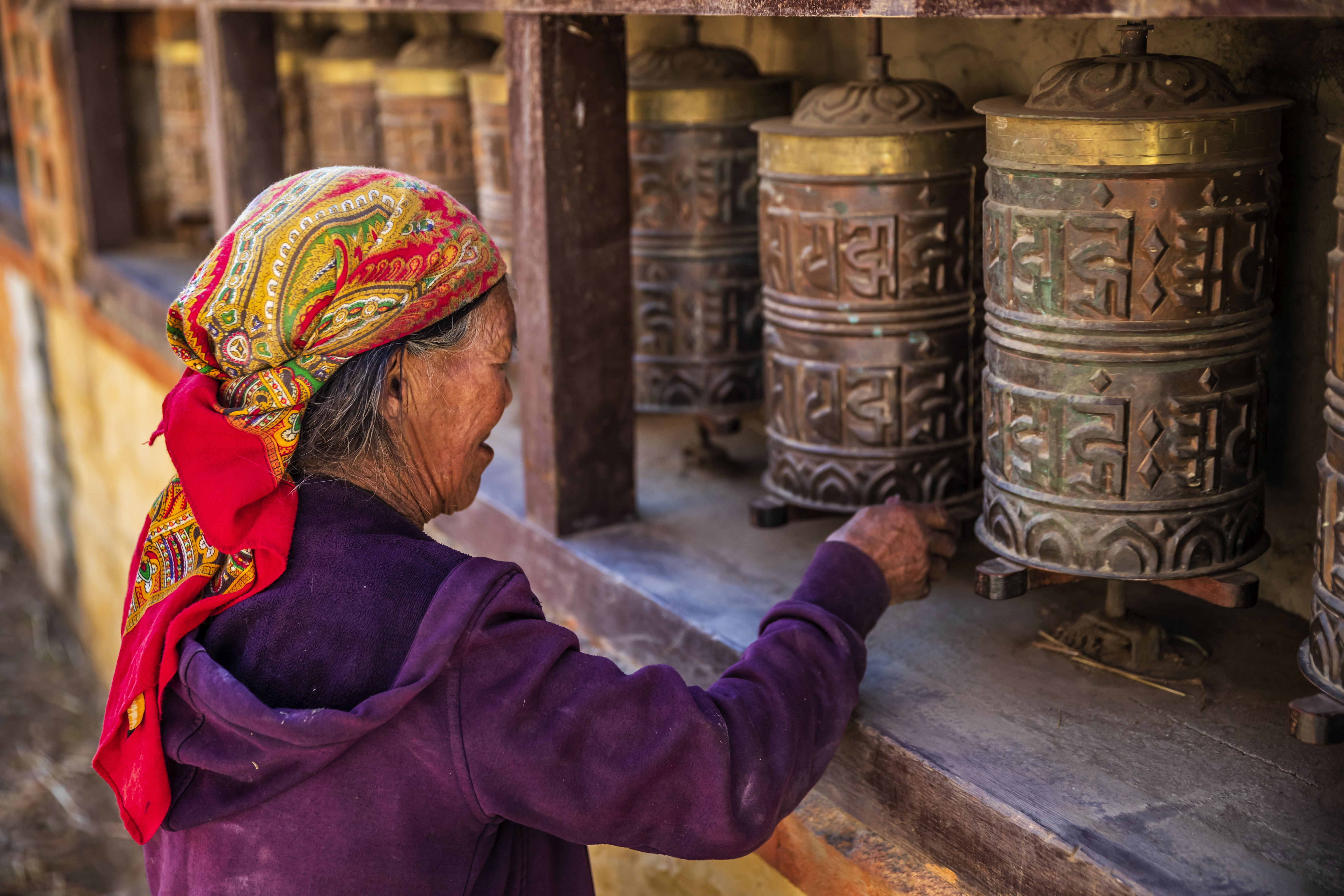 An elderly Tibetan woman turns prayer wheels in Upper Mustang, preserving centuries-old Buddhist traditions in Nepal