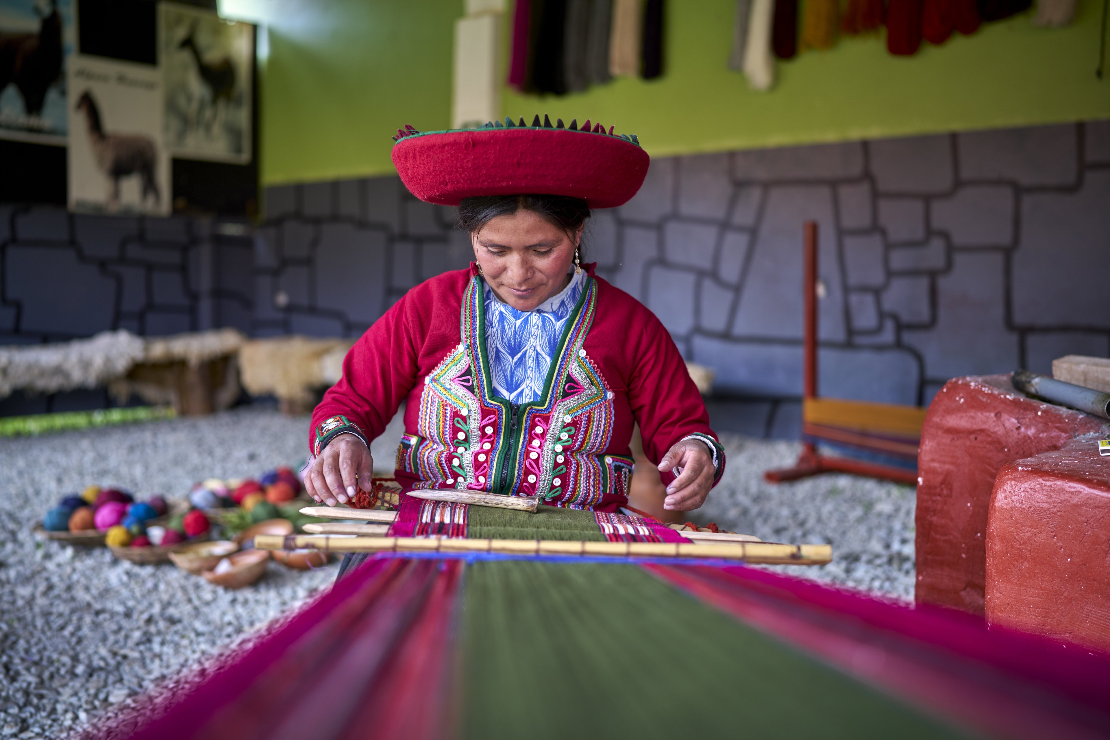 Peruvian woman from the town of Chinchero weaving traditional cloth made with alpaca animal hair
