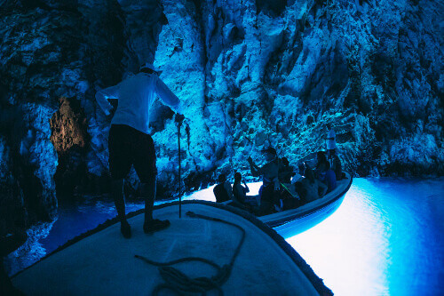 Tourist visiting the inside of the Blue Cave or Blue Grotto in Bisevo Island.
