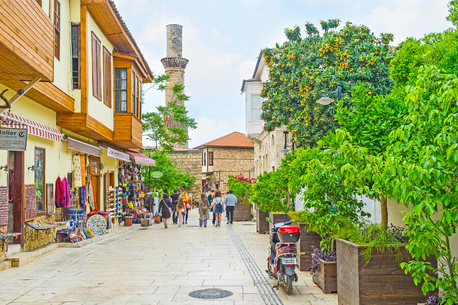 The Kesik Minare Cami is in the distance as tourists and locals walk down a busy street.
