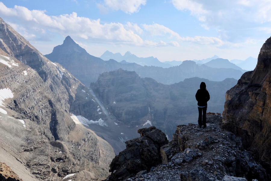 A hiker enjoys the view on the edge of Abbot Pass, overlooking Mount Lefroy.