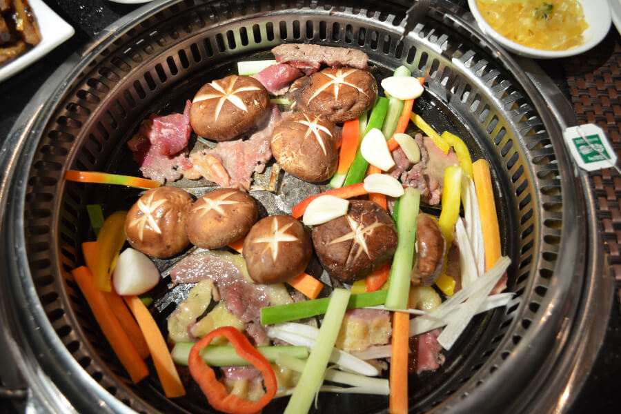 Meat and cooked vegetables in the table at a Mongolian barbeque grill