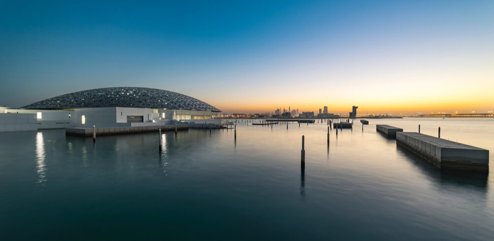 Sunset over the sea at the Louvre Abu Dhabi, a must-visit cultural attraction during your stopover
