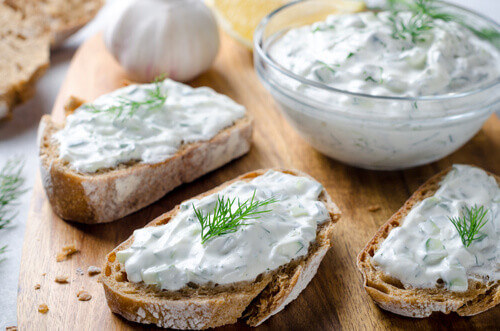 Homemade Greek Tzatziki Sauce served in a glass bowl with sliced bread.