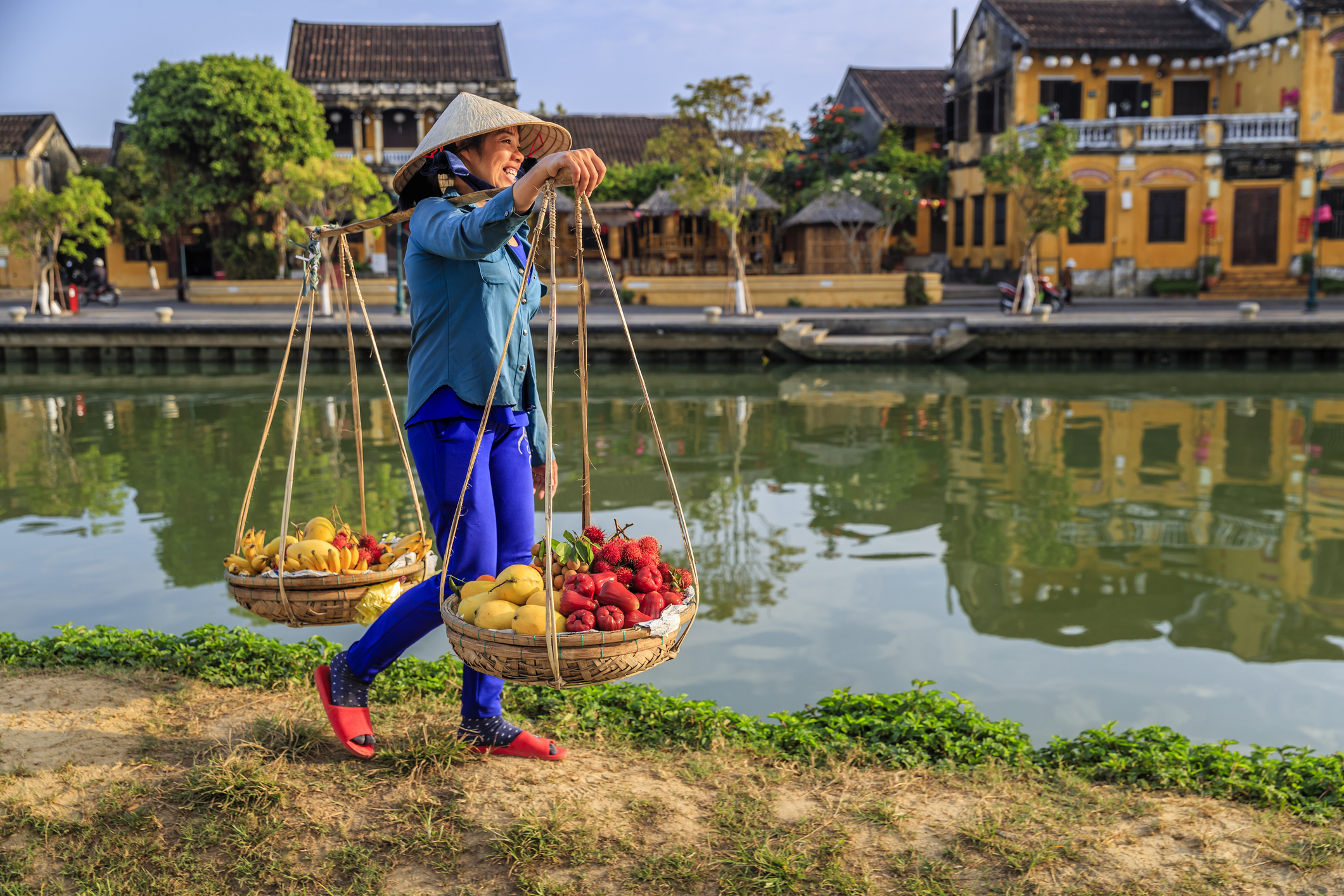 A Vietnamese woman selling colourful fruit along the river bank in Hoi An