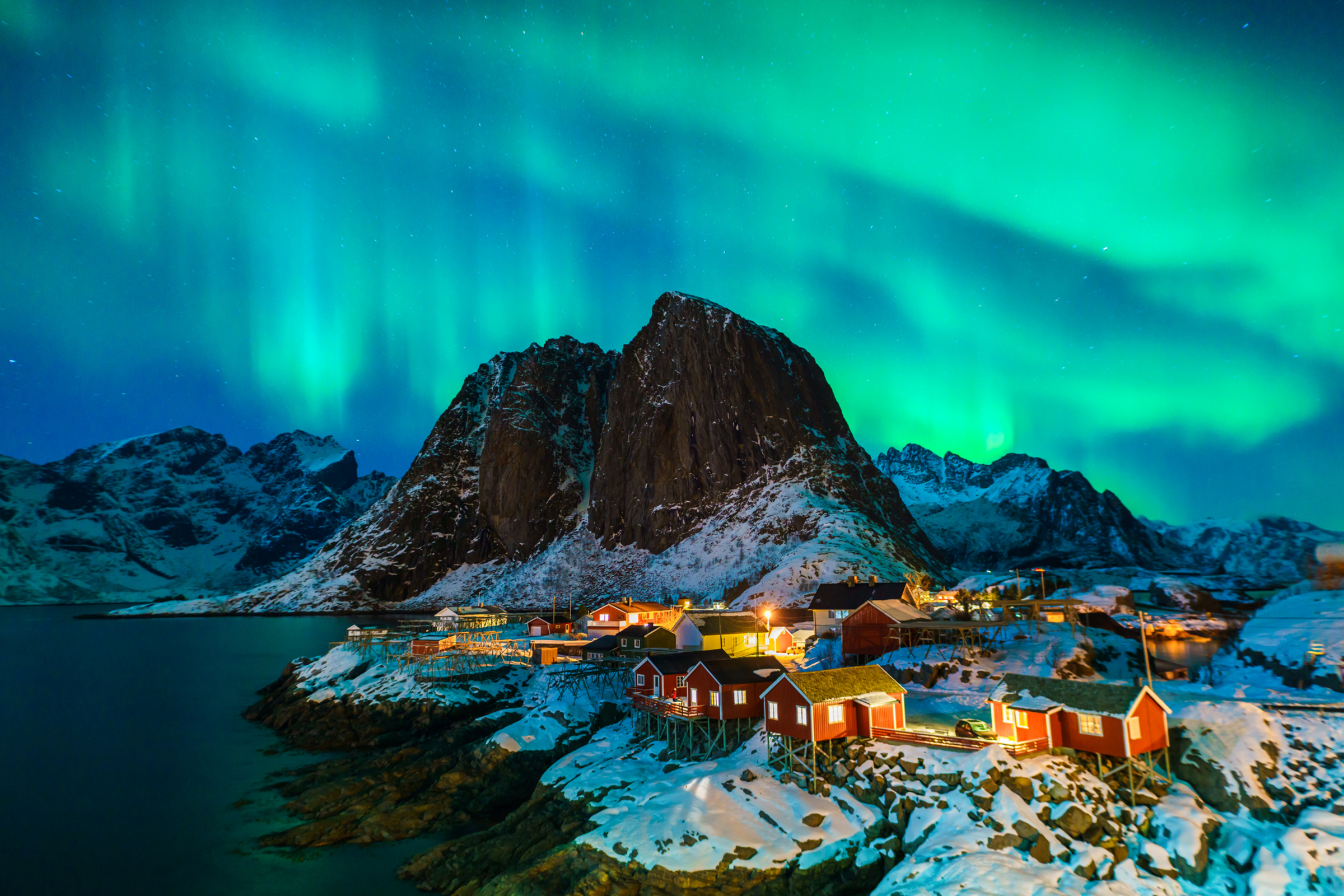 Snow-covered peaks and fjords of Norway&rsquo;s Lofoten Islands glowing under the northern lights in January, the perfect winter destination for snowshoeing, igloo stays and Arctic scenery.