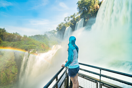A woman stands close to Iguazu Falls, taking in the natural beauty.