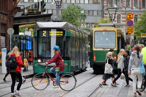 A woman on a bike crosses in front of a tram with others in the Old Town, Helsinki.