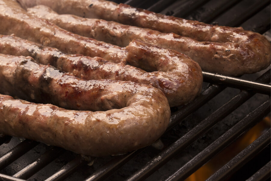Boerewors sizzling on a gas braai, a staple of South African cuisine