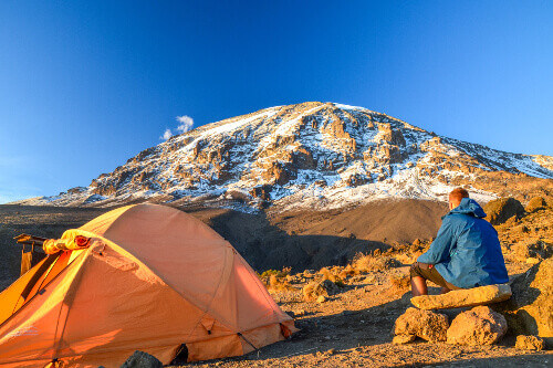 Tourist in Kibo with Uhuru Peak, the highest mountain in Africa, at Mount Kilimanjaro.