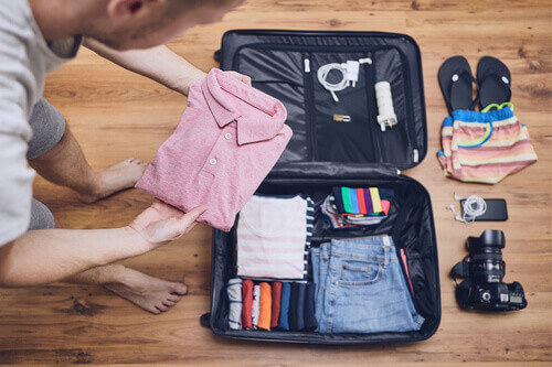 A young man packs clothes for an upcoming vacation.