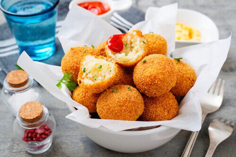 Homemade Italian Fried Risotto Arancini stuffed with cheese and served with tomato sauce