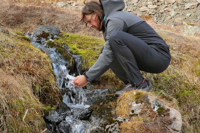 A male hiker drinking fresh water from Iceland;s Highlands near Alftavatn Lake.