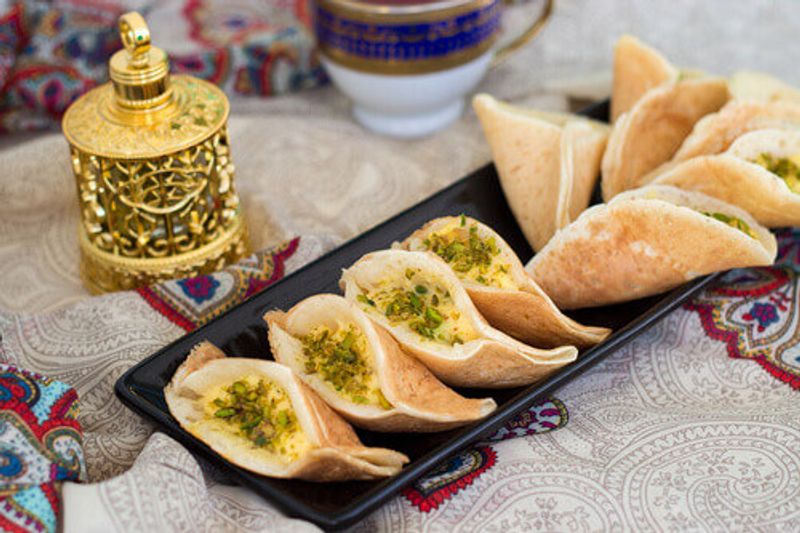 Traditional Arabic Qatayf Crepes stuffed with cream and pistachios prepared for iftar in Ramadan.