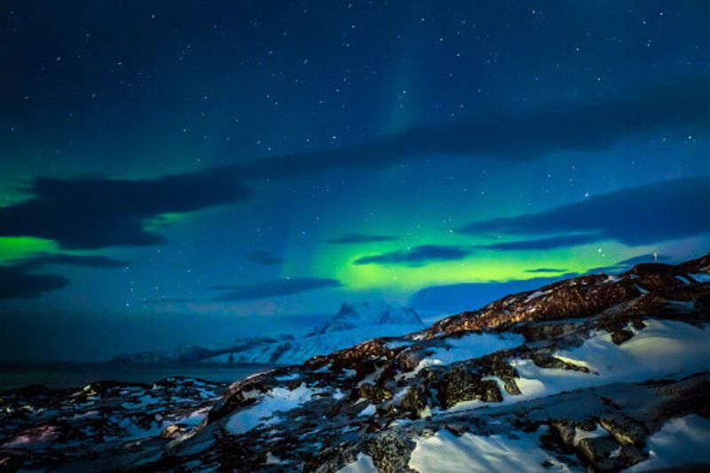 Northern Lights over the fjord and mountains in Nuuk.