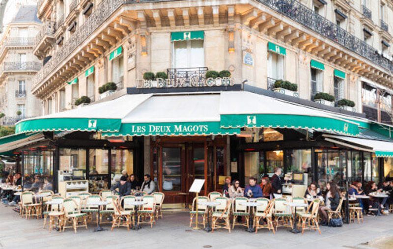 The cafe Les Deux Magots located at the corner of boulevard Saint Germain and rue Saint Benoit in Paris.