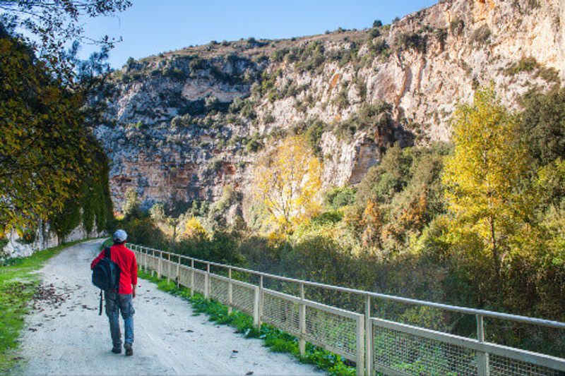 Hiker walking along the trails of the Anapo Valley by the rocky necropolis of Pantalica.