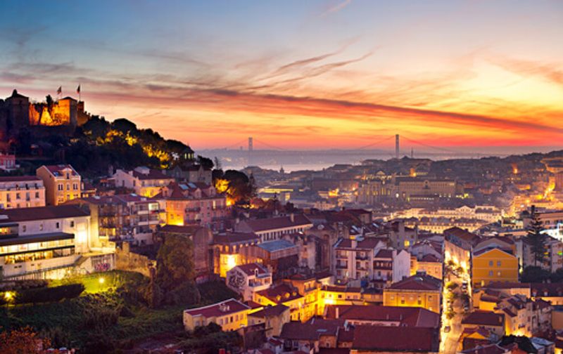 The stunning, picturesque sunset views of the Lisbon skyline beside the ocean.
