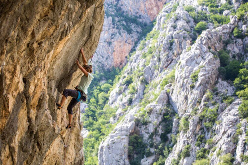 A woman climbs the rocky mountain in the Paklenica National Park.