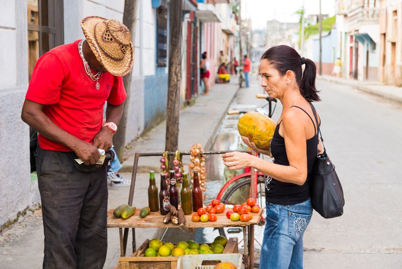 A woman buys fresh fruit from a bicycle street vendor in Havana