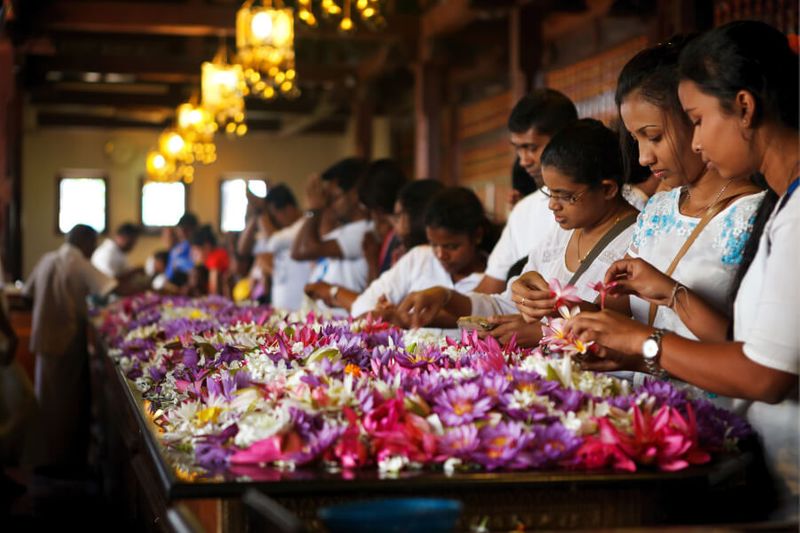 A group of tourists and worshippers inside of the Temple the Sacred Buddha Tooth in Kandy, Sri Lanka.