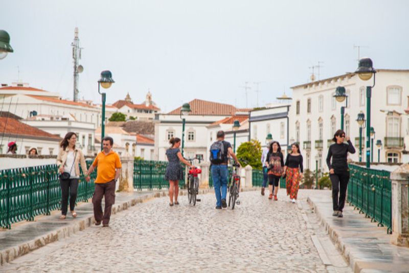 People walk along the Tavira Bridge in Portugal.