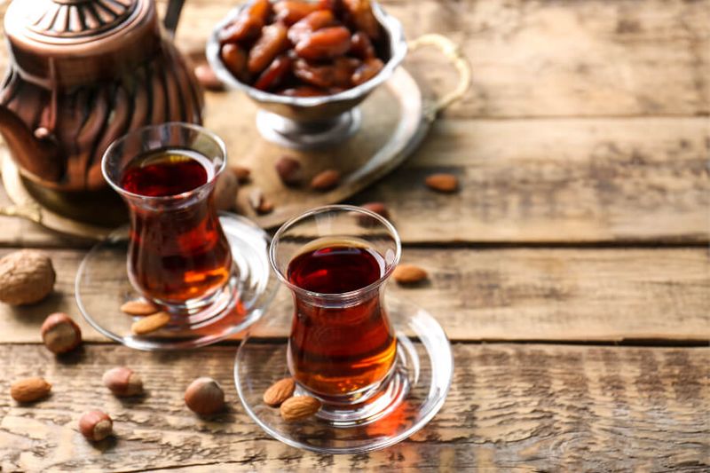 Turkish Tea is presented in traditional glasses with nuts on wooden background.