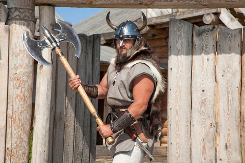 A man dressed in traditional Viking dress with weaponry.