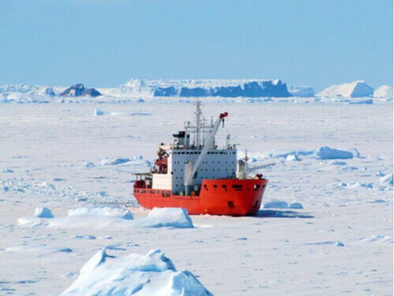 A ship floats amongst ice sheets in Antarctica.