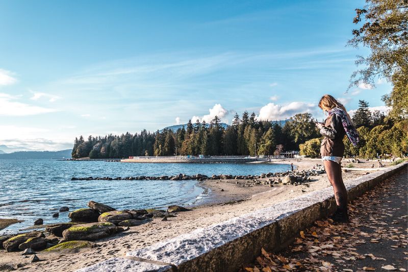 A girl looking at a phone near the Second Beach in Stanley Park.