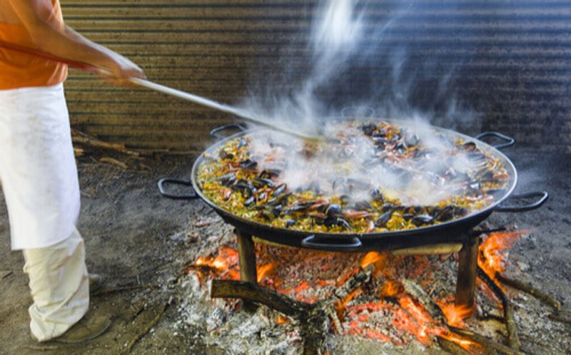 A man cooks a large wok of Paella in Spain.