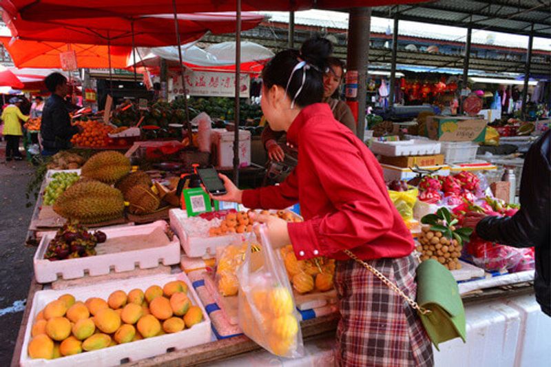 Woman buying fruits at the public market in Lijiang.