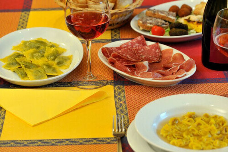 Table set with the typical Italian cuisine of the Emilia Romagna region with Lambrusco wine, cured meats and tortelli.