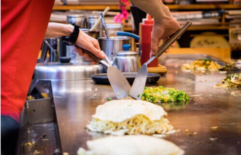 A local cooks Okonomiyaki in Hiroshima, Japan.