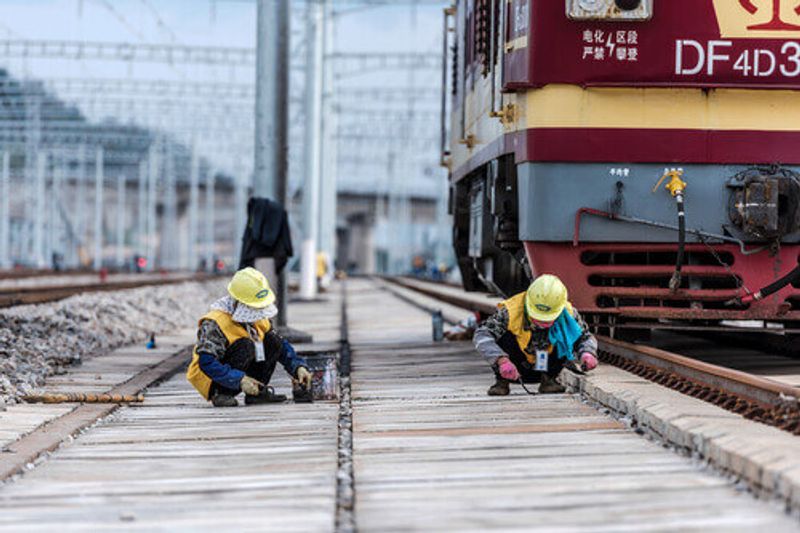 Railway workers maintain high-speed railway tracks at a station in Kunming