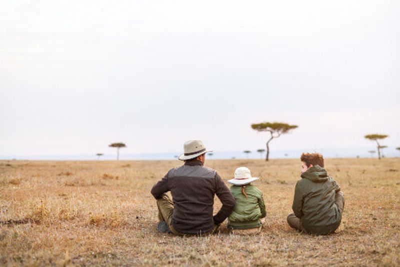 A family on an African safari vacation enjoying views over Masai Mara.