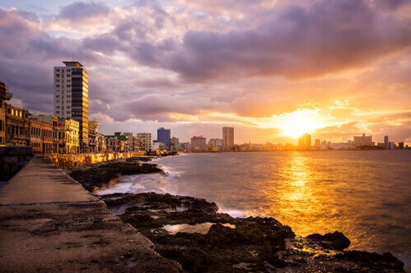 The Malecon seawall in Havana during a beautiful sunset with a view of the city skyline.