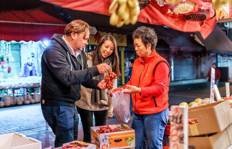 A young couple purchase fruit while at a quaint outdoor food market in China.