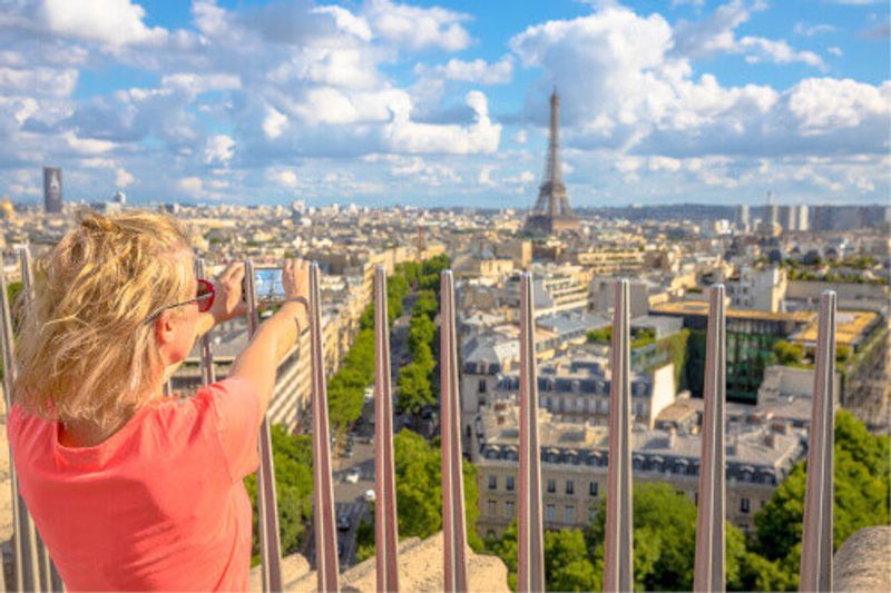 A tourist taking an image on the top of the Arc de Triomphe.