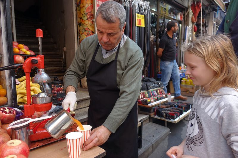 A child buys fresh pomegranate juice from a vendor.