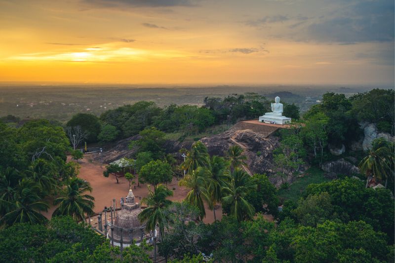 Aradhana Gala Rock overlooks the plain with a Buddha Statue in the distance, in Mihintale, Sri Lanka.